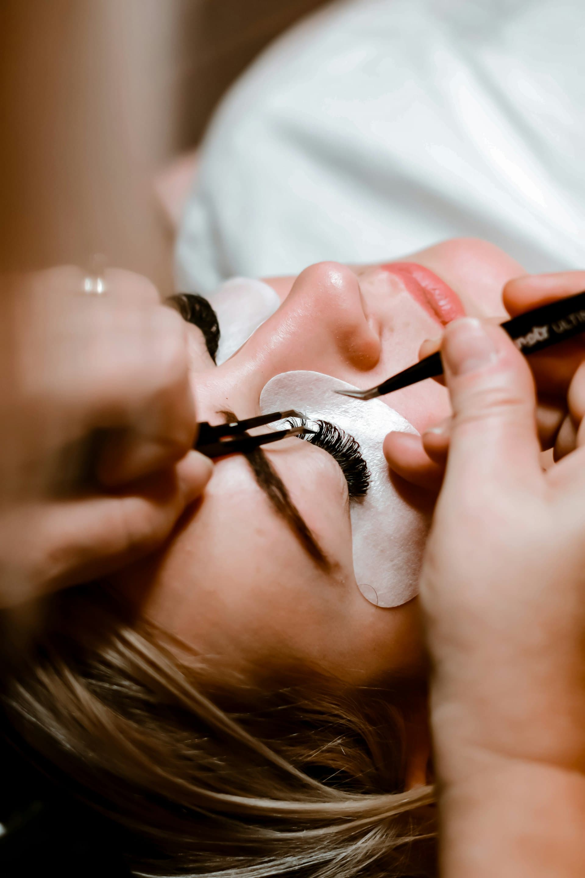 Technicienne en extensions de cils au travail sur une cliente en institut